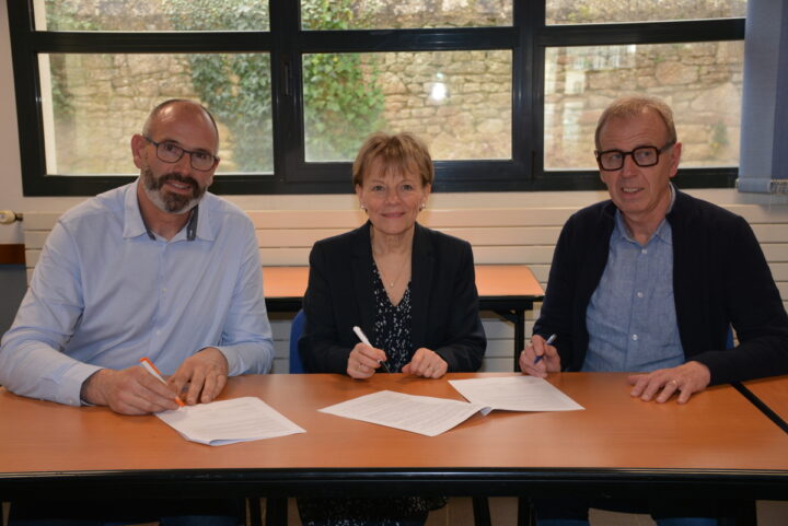 Trois personnes signent un partenariat