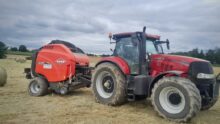 roundballer Kuhn attelé à un tracteur Case sur une parcelle