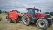 roundballer Kuhn attelé à un tracteur Case sur une parcelle