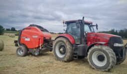 roundballer Kuhn attelé à un tracteur Case sur une parcelle