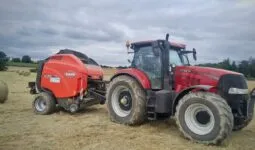 roundballer Kuhn attelé à un tracteur Case sur une parcelle