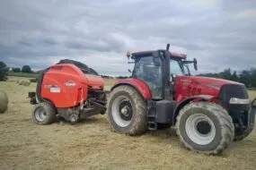 roundballer Kuhn attelé à un tracteur Case sur une parcelle