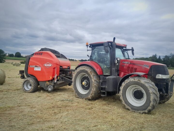 roundballer Kuhn attelé à un tracteur Case sur une parcelle