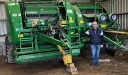 Un éleveur devant deux outils pour presser de l'herbe.