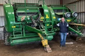 Un éleveur devant deux outils pour presser de l'herbe.