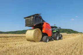 Une presse à balles rondes à chambre variable Kuhn au travail dans un champ