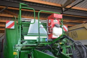 Réserve d’eau et d’inoculant SLV Applipro installée à l’avant d'une presse enrubanneuse.