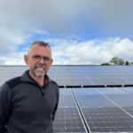 Un homme devant un champ de panneaux solaires en toiture