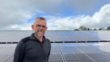 Un homme devant un champ de panneaux solaires en toiture