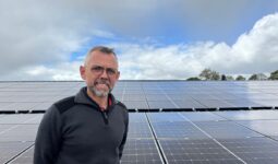Un homme devant un champ de panneaux solaires en toiture
