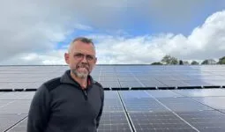 Un homme devant un champ de panneaux solaires en toiture