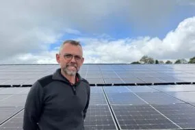 Un homme devant un champ de panneaux solaires en toiture