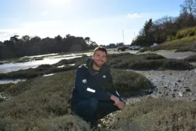 Ewen Frin en train de récolter des herbes marines sur une plage