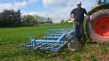 Un agriculteur devant sa herse étrille