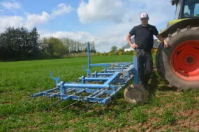 Un agriculteur devant sa herse étrille