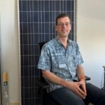 Un homme assis devant un panneau solaire