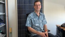 Un homme assis devant un panneau solaire