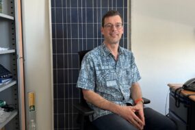 Un homme assis devant un panneau solaire