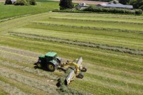 Vue aérienne d'un tracteur au champ avec un andaineur à tapis