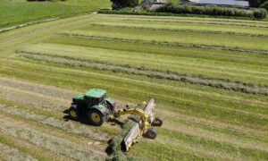 Vue aérienne d'un tracteur au champ avec un andaineur à tapis
