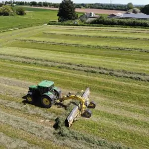 Vue aérienne d'un tracteur au champ avec un andaineur à tapis