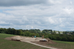 Un chantier de terrassement de bâtiment agricole au milieu de champs de maïs