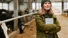 Portrait d'une jeune femme agronome avec une tablette debout dans une stabulation avec des vaches