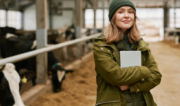 Portrait d'une jeune femme agronome avec une tablette debout dans une stabulation avec des vaches