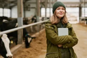 Portrait d'une jeune femme agronome avec une tablette debout dans une stabulation avec des vaches