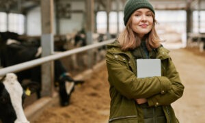 Portrait d'une jeune femme agronome avec une tablette debout dans une stabulation avec des vaches
