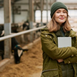 Portrait d'une jeune femme agronome avec une tablette debout dans une stabulation avec des vaches
