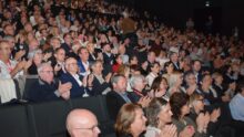 Une foule dans un amphithéâtre assise sur des fauteuils