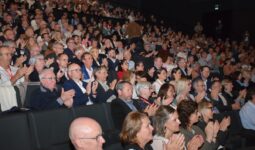 Une foule dans un amphithéâtre assise sur des fauteuils