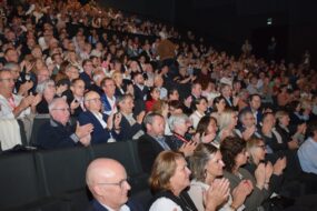 Une foule dans un amphithéâtre assise sur des fauteuils