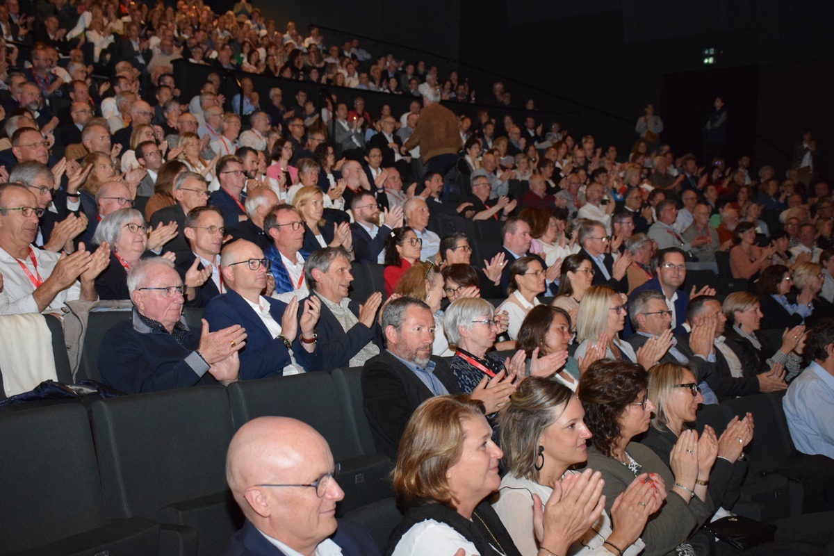 Une foule dans un amphithéâtre assise sur des fauteuils - Illustration Sous le signe de la confiance