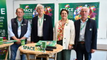 Les responsables du space derrière une table et devant les panneaux de l'affiche 2025