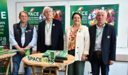 Les responsables du space derrière une table et devant les panneaux de l'affiche 2025