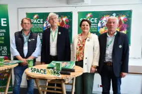 Les responsables du space derrière une table et devant les panneaux de l'affiche 2025
