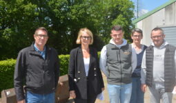 Des personnes devant un talus et un bâtiment agricole