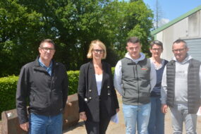 Des personnes devant un talus et un bâtiment agricole