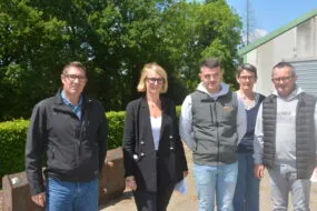 Des personnes devant un talus et un bâtiment agricole