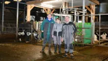 Des agriculteurs dans un bâtiment avec une vache qui entre dans un robot de traite
