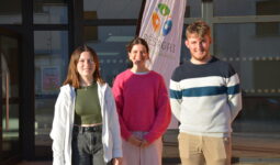Trois étudiants devant un bâtiment scolaire