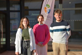 Trois étudiants devant un bâtiment scolaire