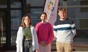 Trois étudiants devant un bâtiment scolaire