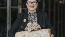 Une femme présente des champignons exotiques ayant poussé sur un susbstrat