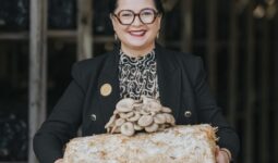 Une femme présente des champignons exotiques ayant poussé sur un susbstrat