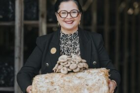 Une femme présente des champignons exotiques ayant poussé sur un susbstrat