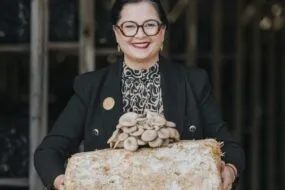 Une femme présente des champignons exotiques ayant poussé sur un susbstrat
