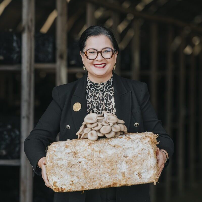 Une femme présente des champignons exotiques ayant poussé sur un susbstrat - Illustration Dans le monde du champignon exotique